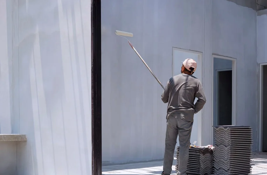 A man painting a wall with a roller.